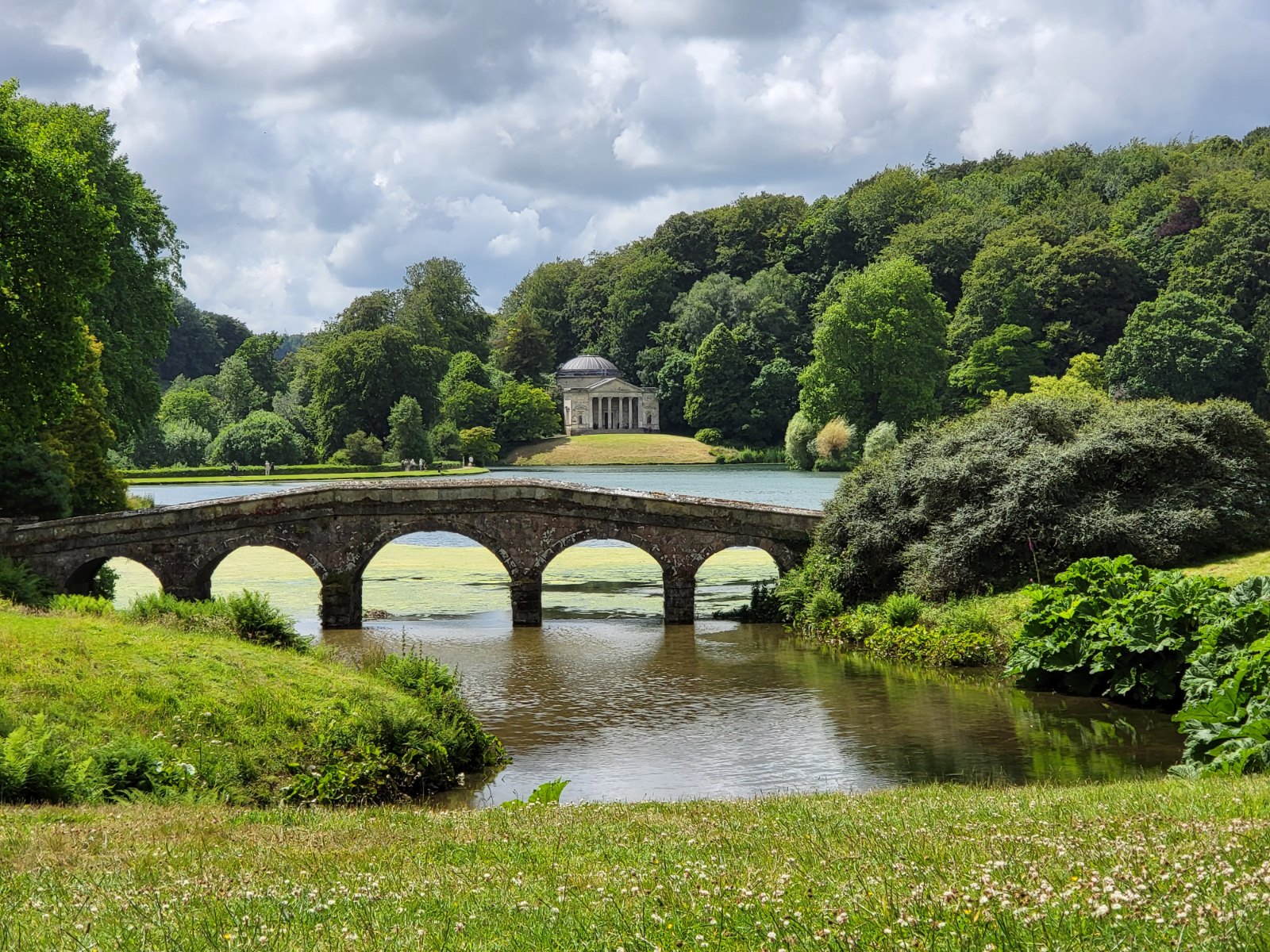 Prima: L’arco di pietra di Stourhead, il lago riflettente, il padiglione classico e il paesaggio giardino di Wiltshire attentamente progettato.
